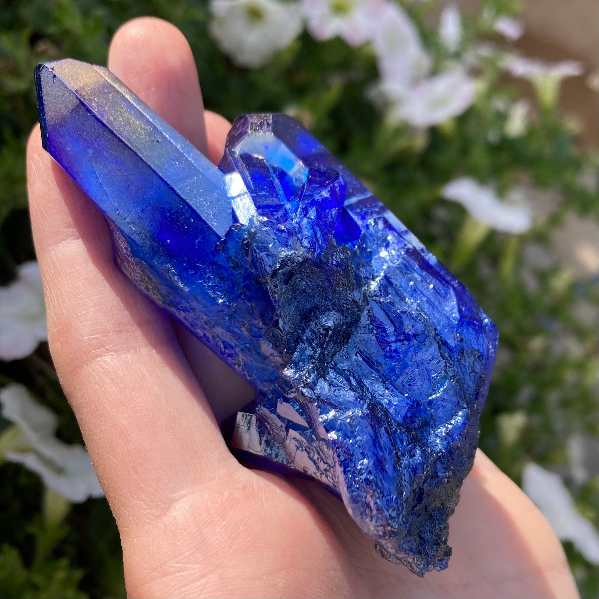 Large aura quartz crystal with flowers in background