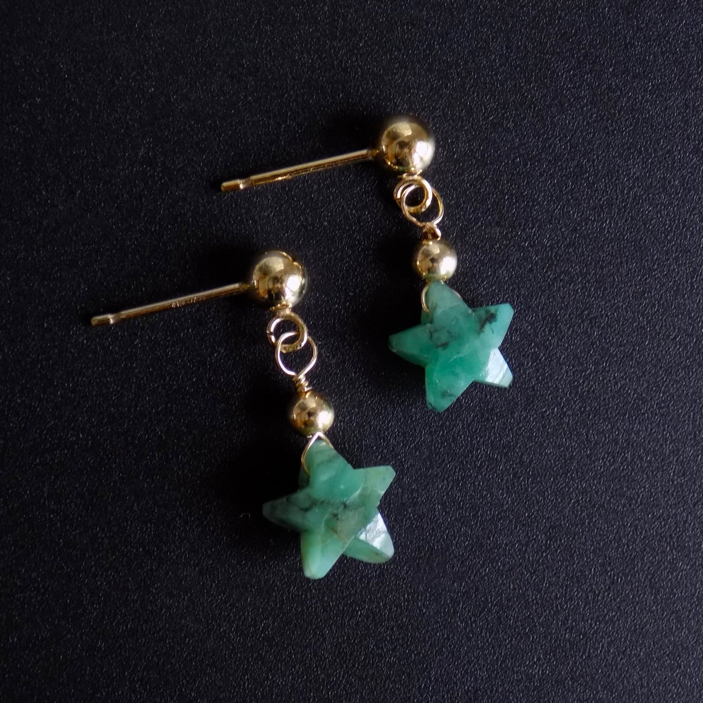 Side view of emerald dangly stud earrings