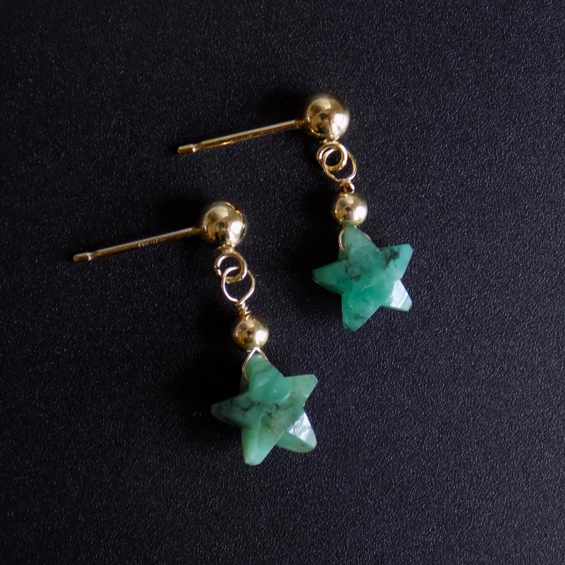 Side view of emerald dangly stud earrings