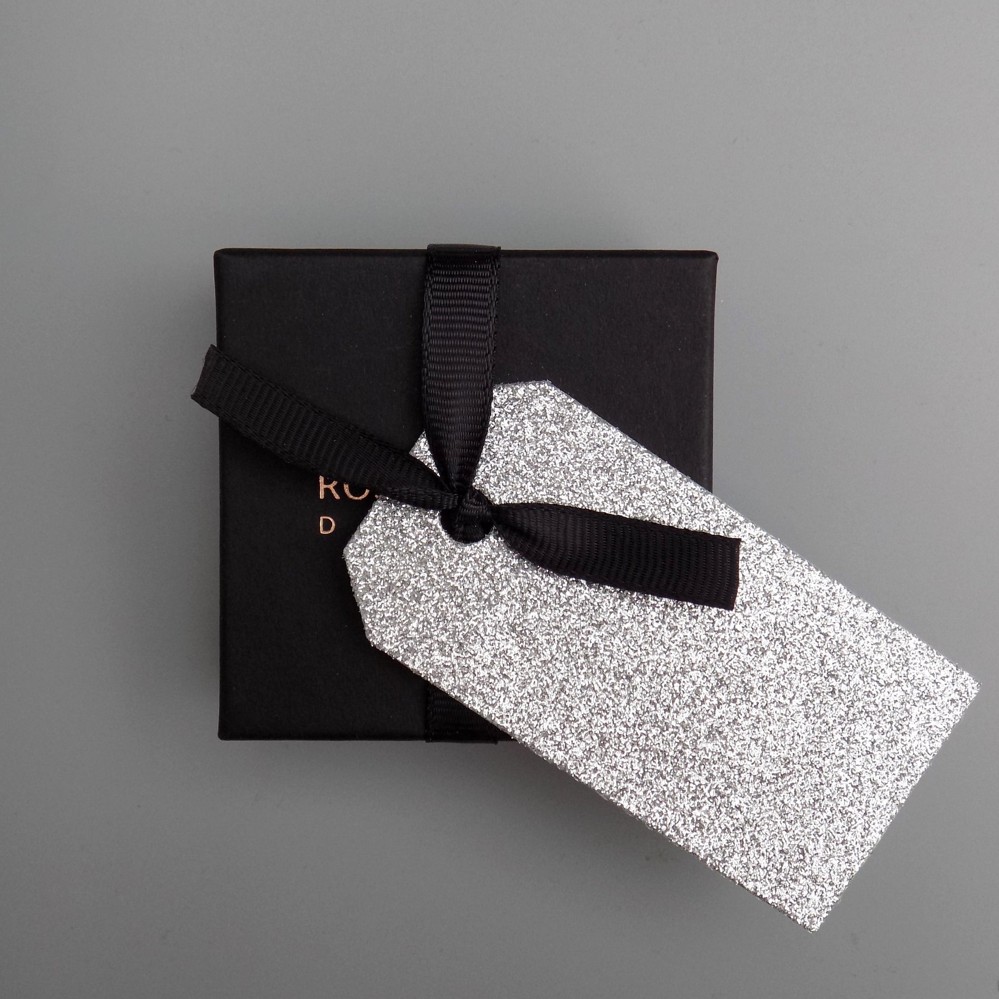 Black gift box with grosgrain ribbon and silver glitter gift tag.