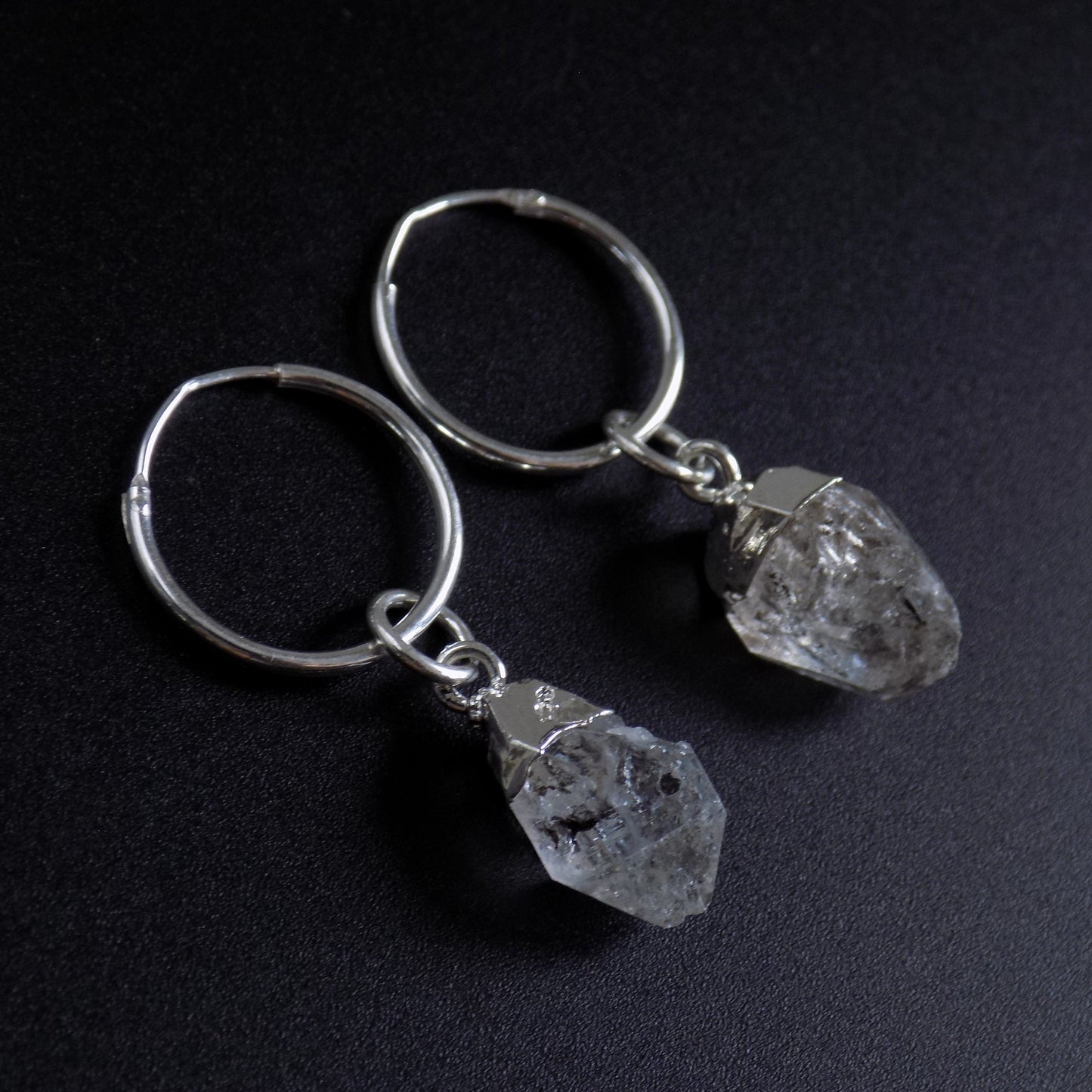 Close up of herkimer hoop earrings, on black background