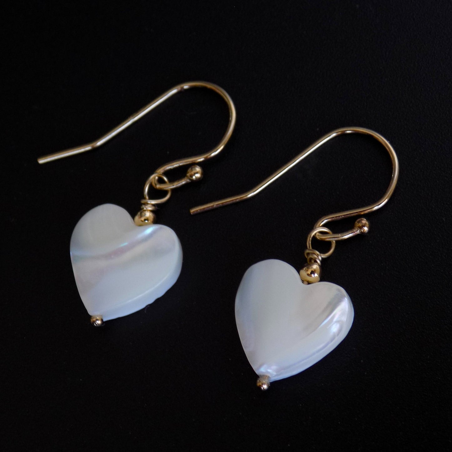 Side view of mother of pearl heart dangly earrings