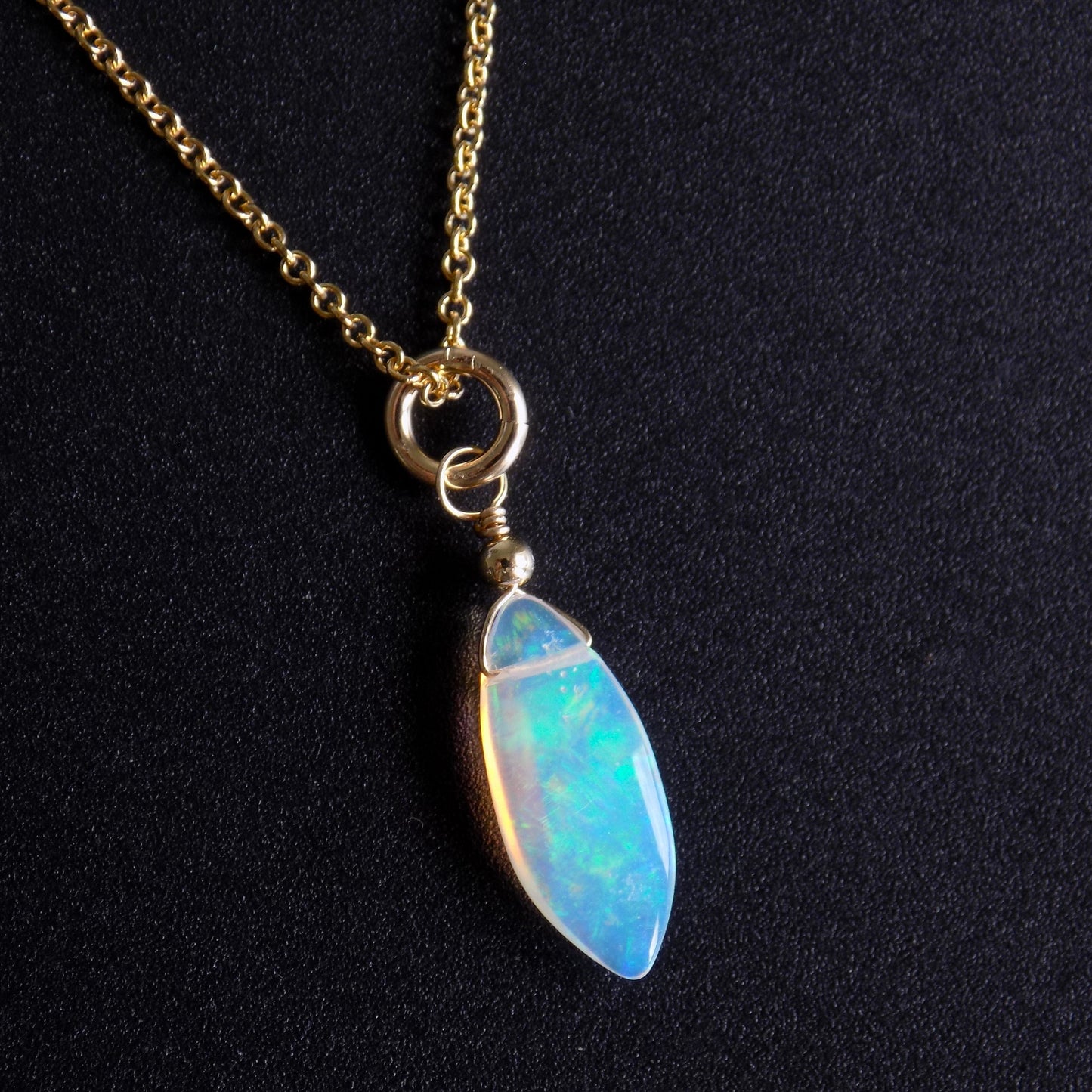 Colourful oval opal pendant, on black background