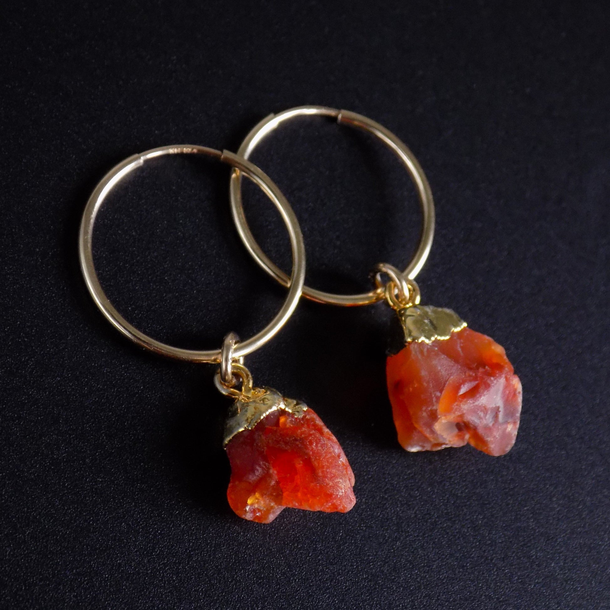 Natural carnelian hoop earrings on black background